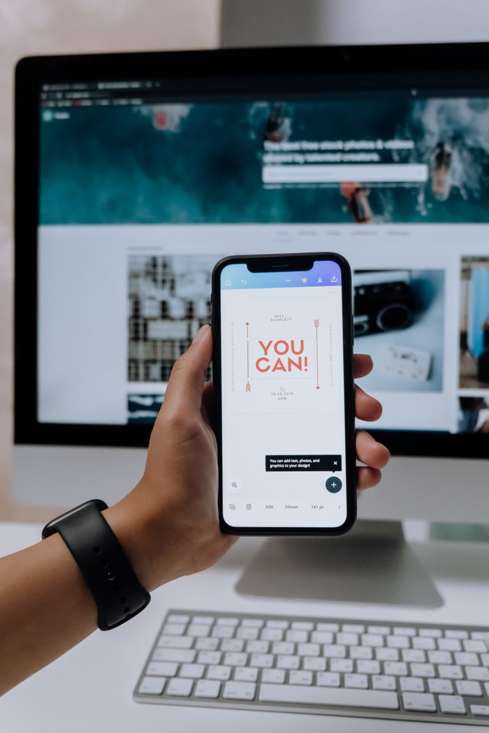 about-02 Hand holding smartphone with 'You Can!' message in front of desktop screen.